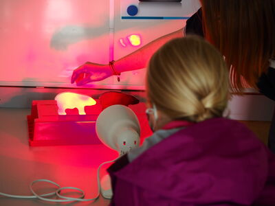 Eine Mitarbeiterin der Zooschule zeigt einem Kind ein Experiment am Forschertag